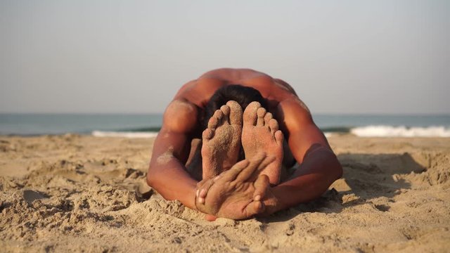A man practices yoga on the beach. Yoga and meditation, self-development