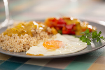 fried egg with brown rice, curry and spicy vegetables on a plate. Selective focus