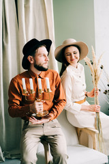 a couple in love in trendy clothes and hats are sitting on a brown sofa, embracing in a spacious beautiful Studio. family concept