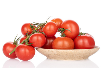 Lot of whole fresh red cherry tomato on vine on ceramic plate isolated on white