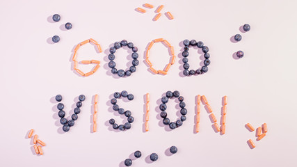 Vitamins and supplements for healthy eyes on pink background. How to maintain good vision concept. Blueberry and orange capsules forming words good vision, flat lay, top view