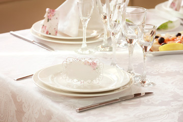 White table setting from above. Elegant empty plate, cutlery, napkin and glass on shabby chic or vintage planked wood table.