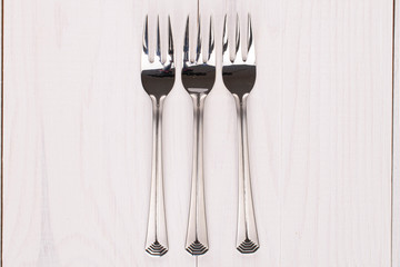 Group of three whole dessert fork on white wood