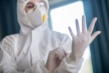 Woman in white workwear looking at her hand in a protective glove