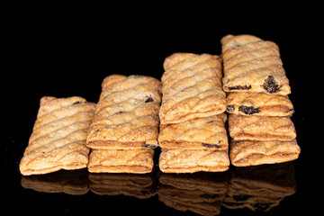 Lot of whole square puff cookie with raisins isolated on black glass