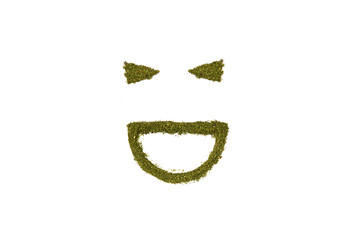 Laughing smiling face wink from grinded marijuana on white background