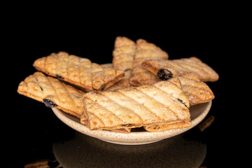 Lot of whole square puff cookie with raisins on plate isolated on black glass
