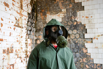 Dramatic portrait of a man wearing a gas mask in a ruined building.