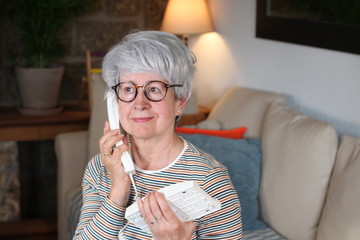 Senior woman using landline telephone