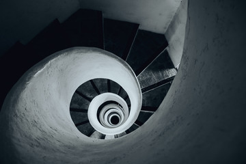 Black and white image of spiral stairs looking down from the top, creating an interesting perspective. 