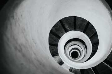 Black and white image of spiral stairs looking down from the top, creating an interesting perspective. 