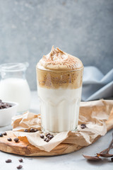 Dalgona creamy coffee in a glass on a light gray background with whipped foam. Korean food trend, Vertical format