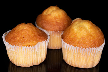 Group of three whole small baked muffin isolated on black glass