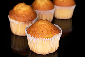 Group of four whole small baked muffin isolated on black glass