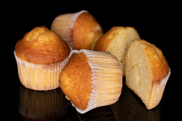 Group of three whole two halves of small baked muffin isolated on black glass