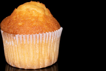 One whole small baked muffin closeup isolated on black glass