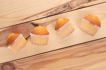 Group of four whole small baked muffin on wood