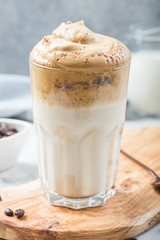 Dalgona frothy coffee in glass on grey. Trend korean drink latte with foam of instant coffee. Close up.