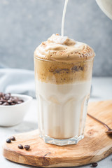 Dalgona frothy coffee in glass on grey. Trend korean drink latte with foam of instant coffee. Close up.