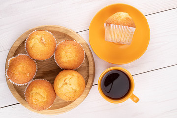 Group of six whole small baked muffin with coffee on white wood