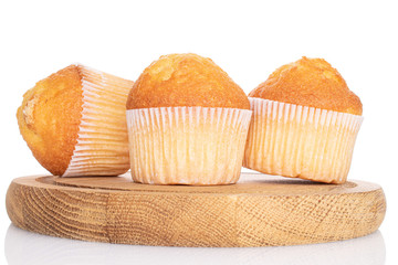 Group of three whole small baked muffin on wooden plate isolated on white
