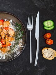 Tasty chicken with rice on brown plate on black background. Europian part of the world.