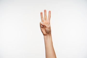 Back view of young woman's hand showing signs of counting with fingers, forming numer three while isolated against white background. Body language concept