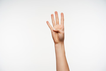 Horizontal shot of raised young pretty lady's hand showing up four fingers while demonstrating counting gestures, isolated over white background
