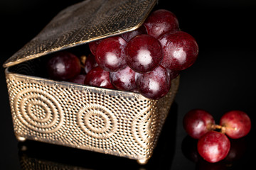 Lot of whole fresh red globe grape in casket isolated on black glass