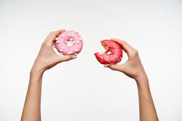 Raised elegant female's hands with white manicure holding fresh donats while going to have...