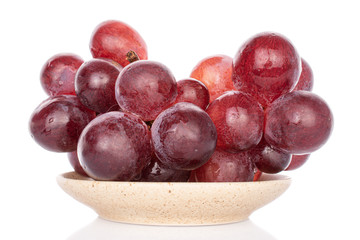 Lot of whole fresh red globe grape on plate isolated on white