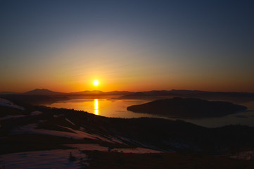 Naklejka na ściany i meble The rising sun illuminating Lake Kussharo. Scenery of dawn from Bihoro Pass. Hokkaido, Japan.