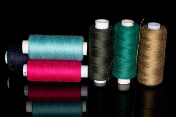 Group of six whole thread spools isolated on black glass