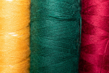 Group of three whole yellow green red thread spool isolated macro