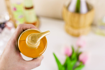 Female hand holds plastic yellow cosmetics jar with liquid soap or lotion for skin care. Skin care mockup.