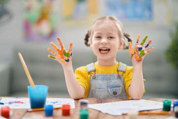 Happy kid is painting at home.
