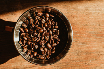 Coffee dripper with roasted coffee bean against  the sunlight in the morning. Top view of coffee dripper with roasted coffee bean on wooden background.
