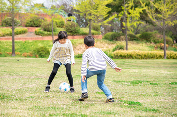 公園でサッカーをする子供