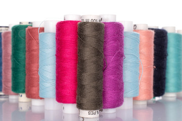 Lot of whole colourful thread spools isolated on white