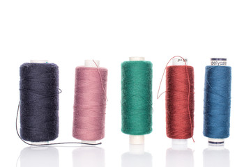 Group of five whole thread spools in row isolated on white