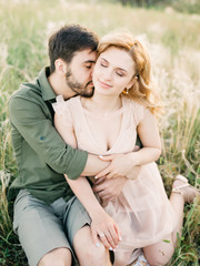 Young couple in love outdoor. Stunning sensual outdoor portrait of young stylish fashion couple posing in summer in field. Film photography. Pretty family hugging and flirting in an park