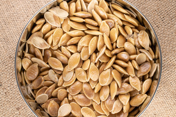 Lot of whole golden pumpkin seed on tan linen