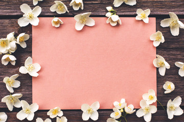 Blank card with white flowers on wooden table.