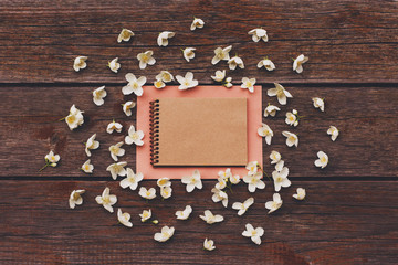 Blank craft sketchbook with white flowers on wooden table.