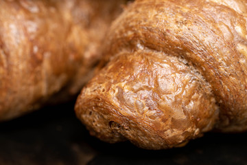 Group of two whole baked wholegrain croissant closeup isolated on black glass