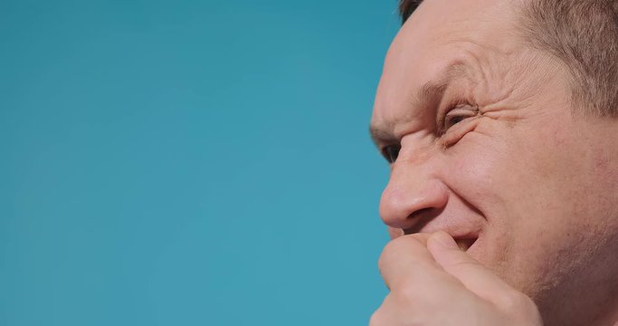 serious blue eyed man picks teeth with fingers standing against studio background slow motion extreme close view