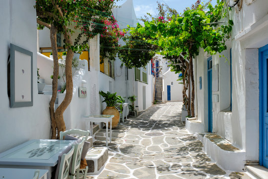 Fototapeta Picturesque narrow street with traditional whitewashed houses with cafe tables of Naousa town in famous tourist attraction Paros island, Greece