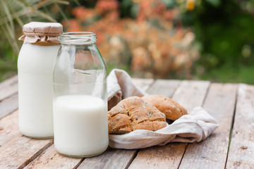 Fresh organic milk in a bottle and round brown rye flatbread on rustic wooden table on nature background. Vegetable milk, vegan milk, Kefir, or Turkish Ayran drink for helthy eating. Space for text