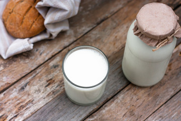 Glass of fresh organic milk and round brown rye fletbread on a rustic wooden table. Kefir, milk or Turkish Ayran drink. Space for text. Top view