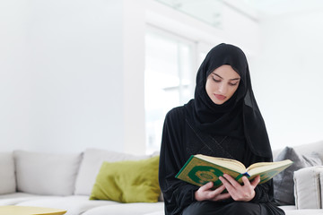 young muslim woman reading Quran at home